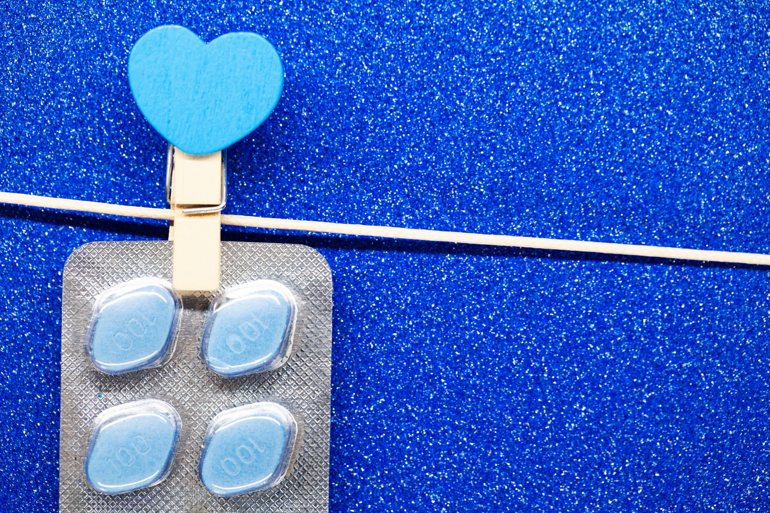 Kamagra vagy Viagra – kék tabletták közelről csillogó háttérrel
